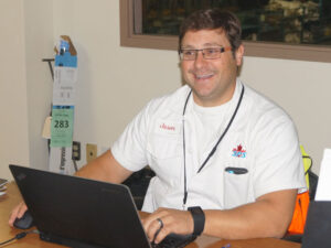 man sitting behind a lap top and smiling