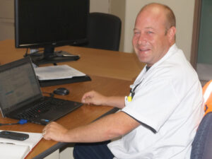 man sitting behind a desk and smiling